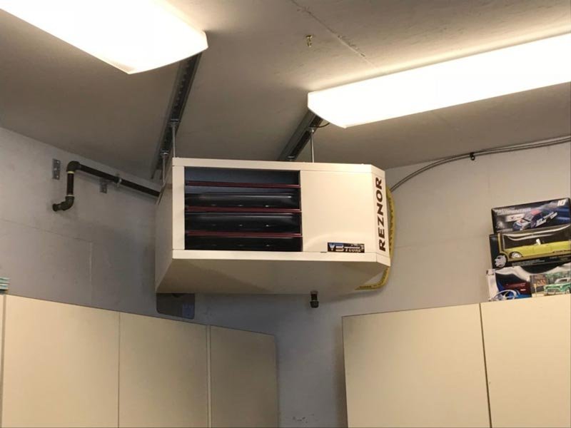 A modern natural gas shop heater installed in a clean, organized professional workshop.